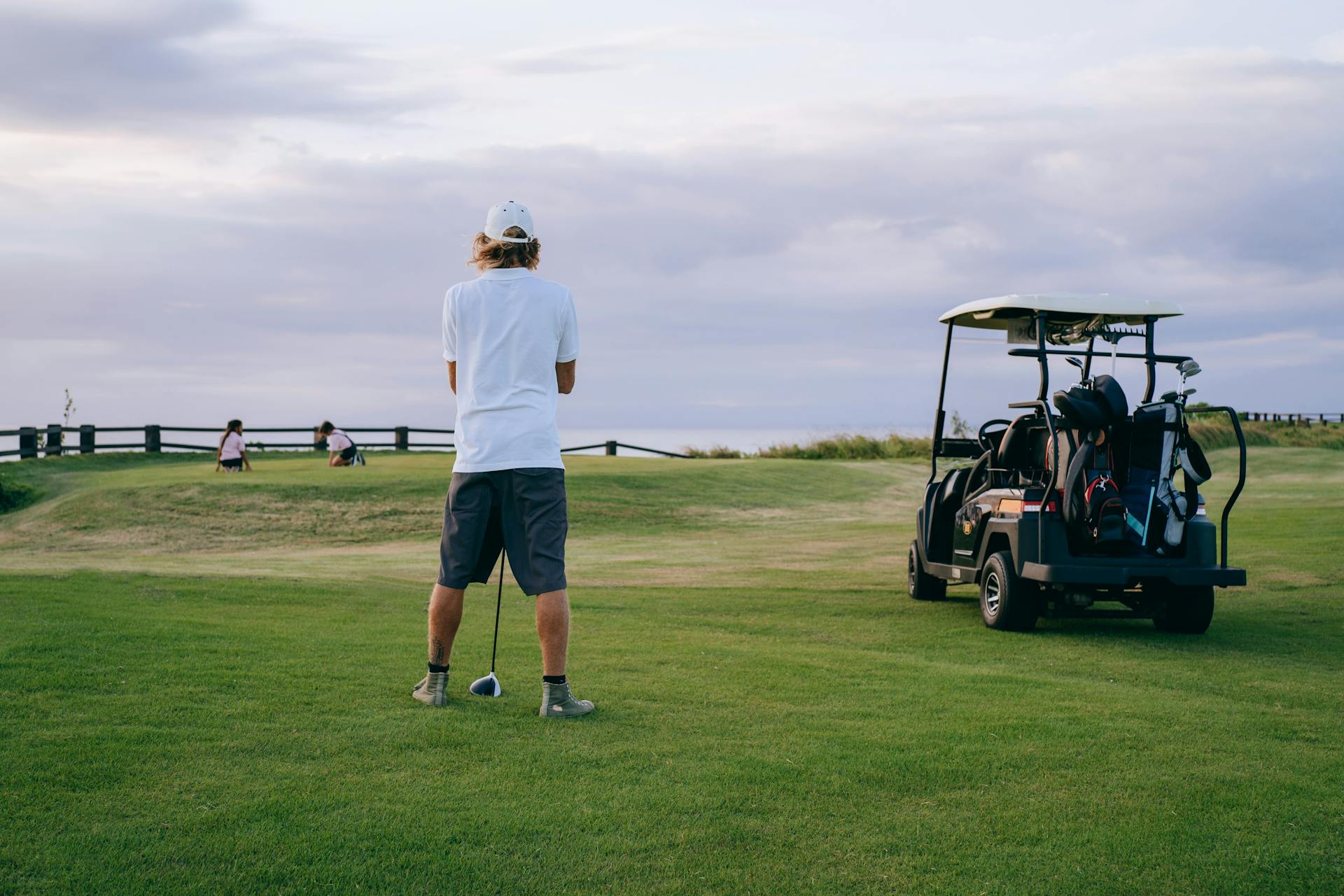 Golfer assessing uphill approach shot on elevated coastal golf course
