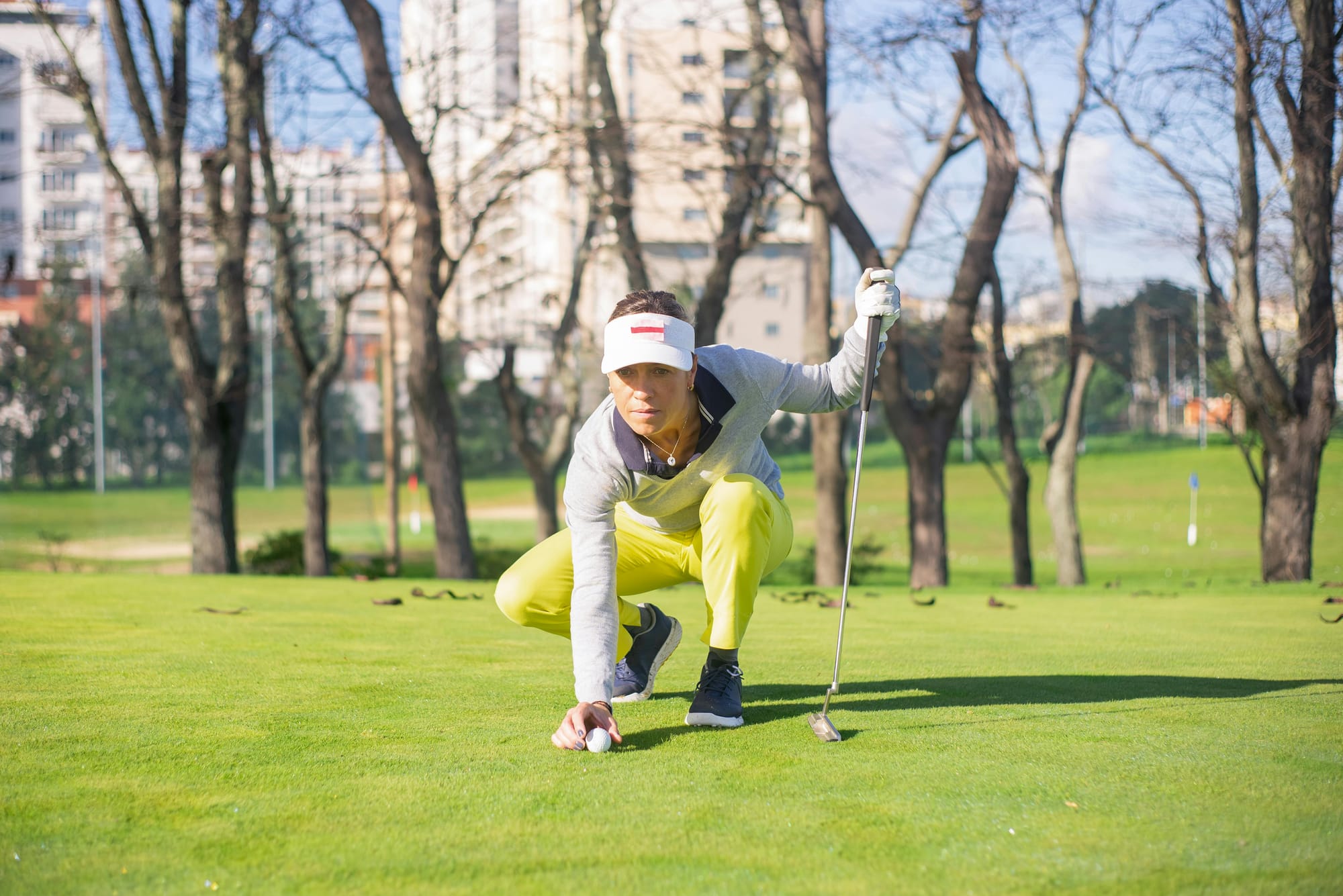 Golfer crouching at ball level to read the line of a putt on a golf green