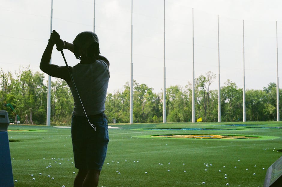 Adult golfer taking a full swing at an outdoor driving range