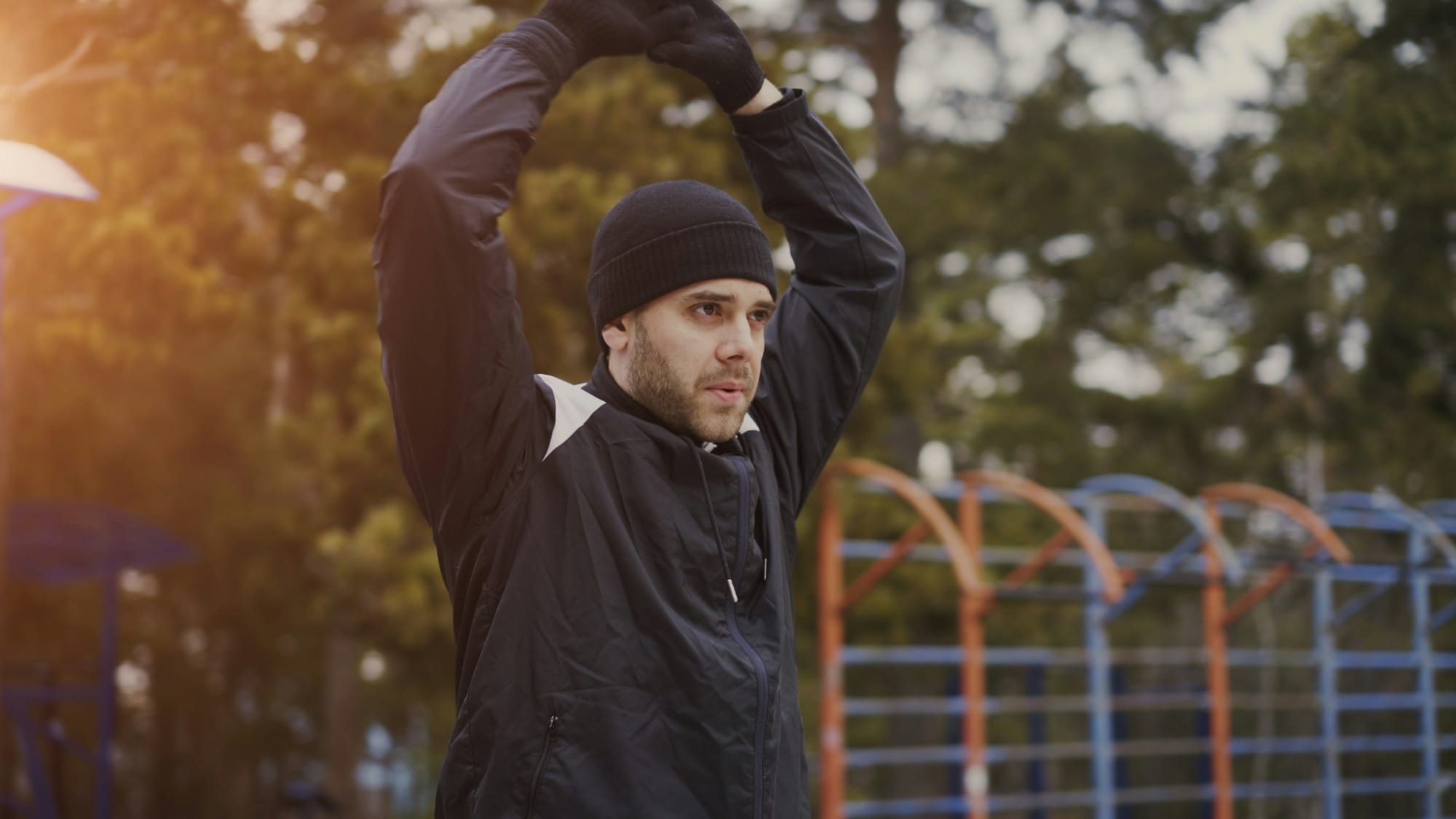 Athlete stretching arms overhead outdoors as part of a mobility warm-up routine