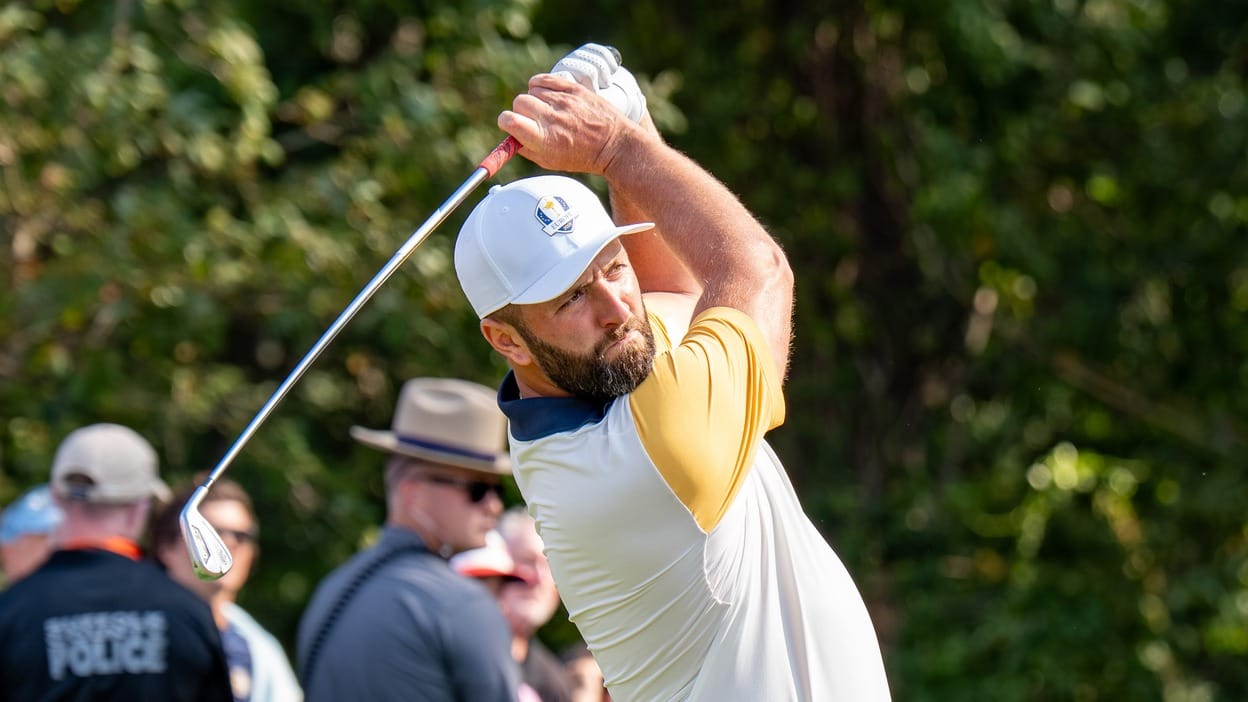 Jon Rahm follows through on a drive in Europe's 2025 Ryder Cup kit, golf club raised overhead.